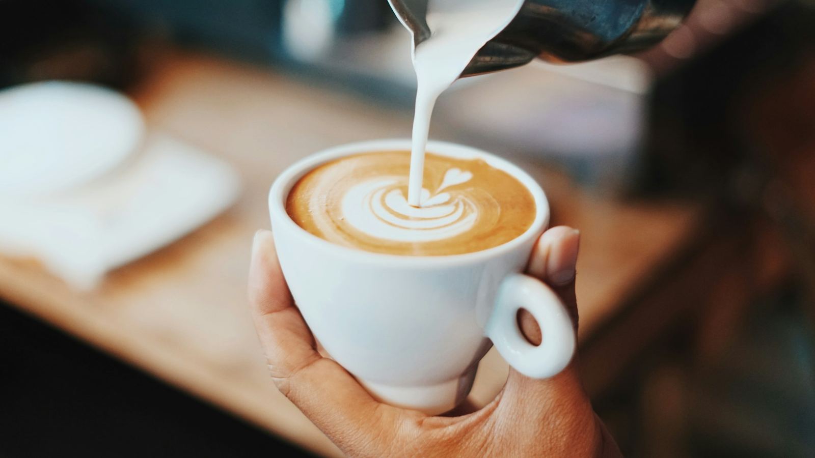 A barista's hands finishing a latte with foam art